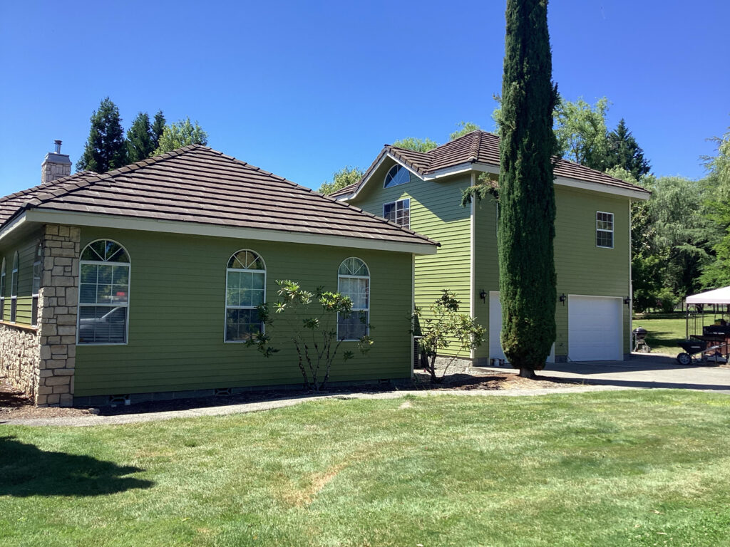Exterior painting project on a green residential home in Southern Oregon with clean siding, detailed trim work, and a freshly finished exterior