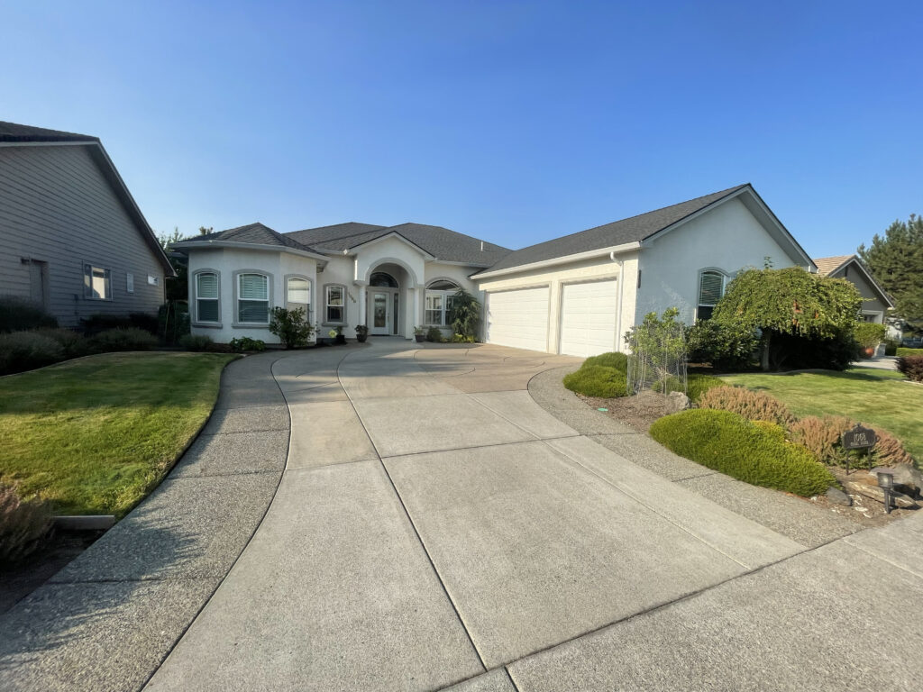 Freshly painted white home exterior with clean driveway and landscaping in Southern Oregon